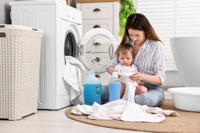 Mother with her daughter washing baby clothes in bathroom