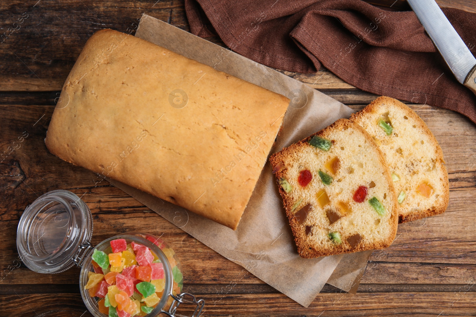 Photo of Delicious cake with candied fruits on wooden table, flat lay