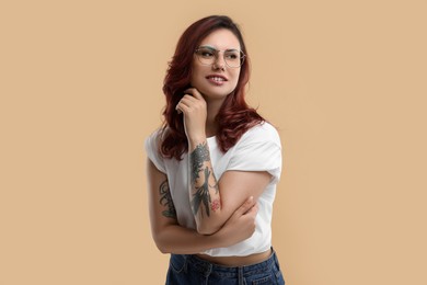 Photo of Portrait of beautiful tattooed woman on beige background