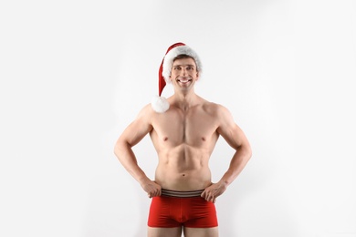 Young muscular man in Santa hat on white background