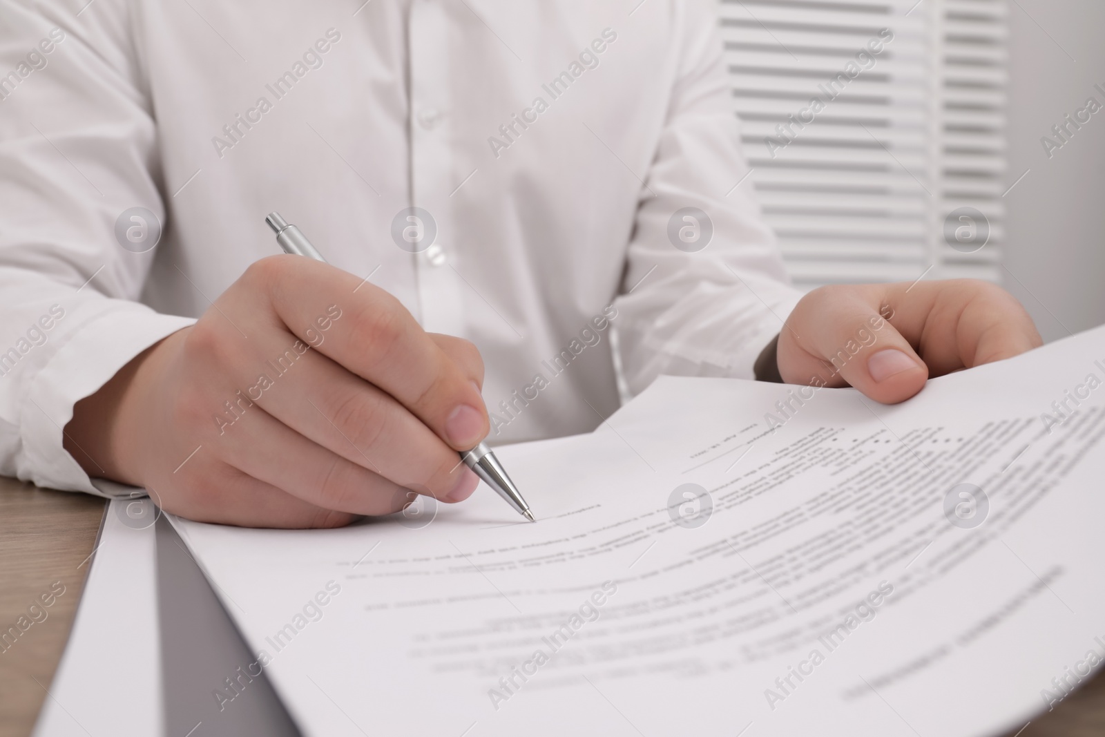 Photo of Man signing document at table, closeup view