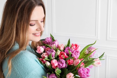 Young woman with bouquet of beautiful tulips indoors