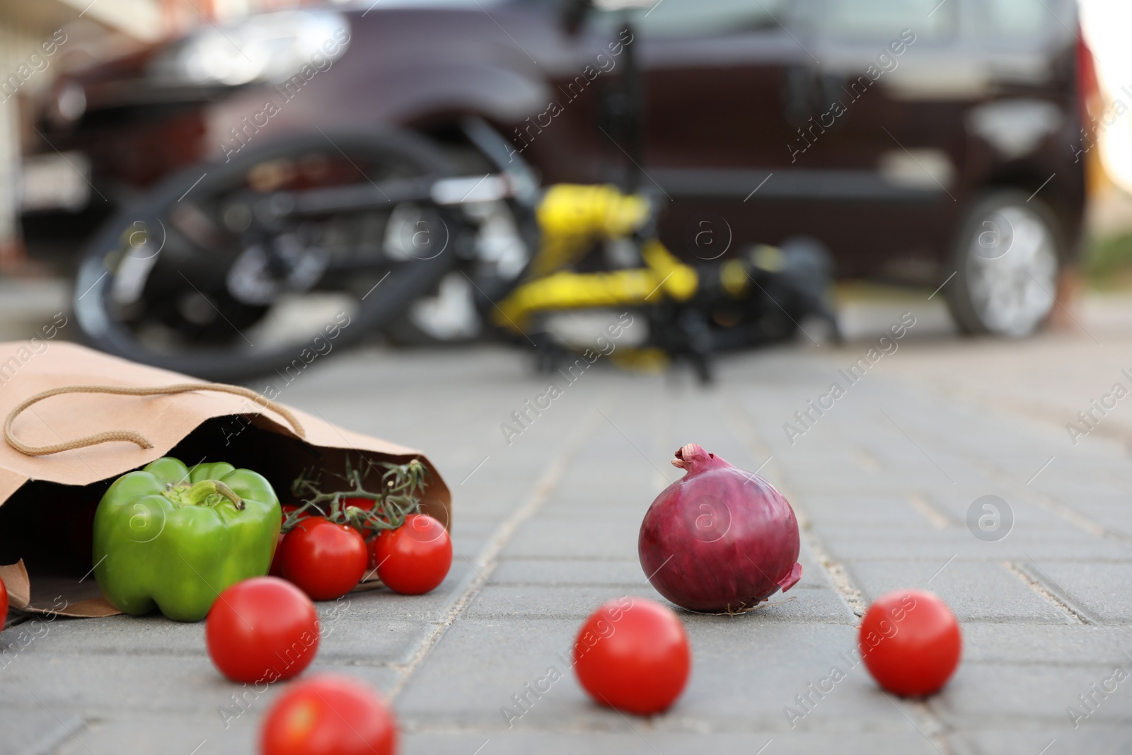 Photo of Fallen bicycle after car accident outdoors, focus on scattered vegetables