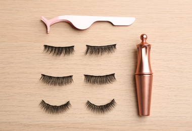 Photo of Flat lay composition with magnetic eyelashes and accessories on wooden table
