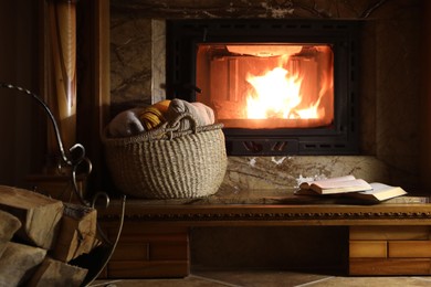 Photo of Sweaters, books and firewood near fireplace at home