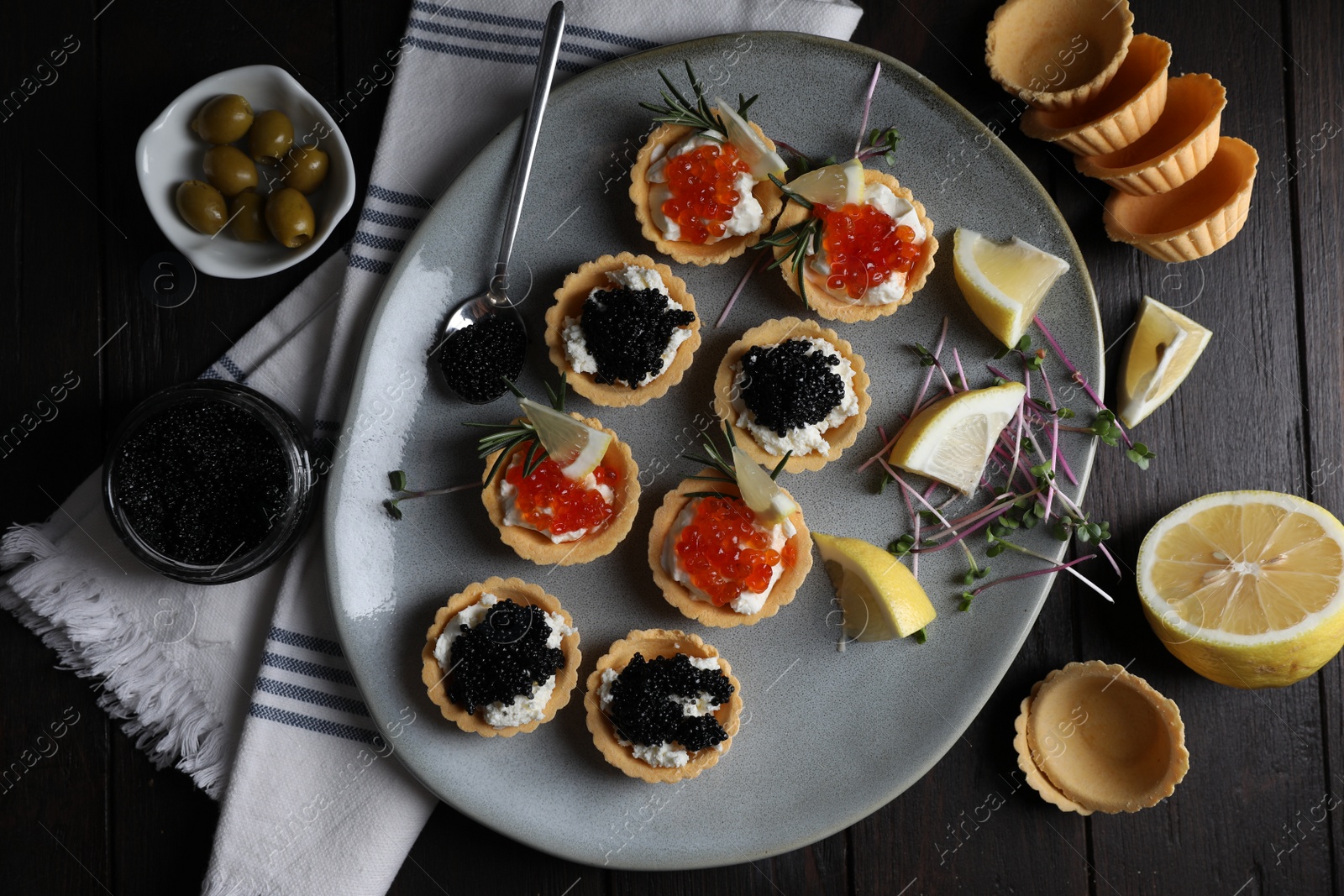 Photo of Delicious tartlets with red and black caviar served on wooden table, flat lay