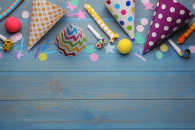 Flat lay composition with party hats and other festive items on light blue wooden background. Space for text