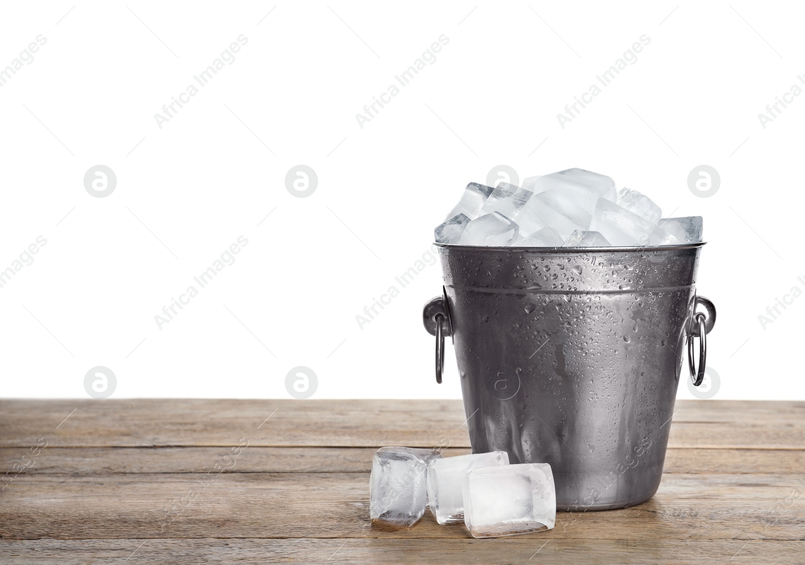 Photo of Metal bucket with ice cubes on wooden table against white background