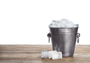 Photo of Metal bucket with ice cubes on wooden table against white background