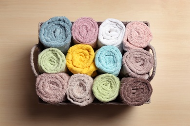 Photo of Wicker basket with clean soft towels on wooden table, top view