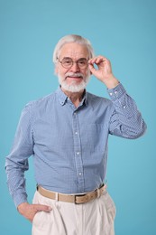 Portrait of stylish grandpa with glasses on light blue background