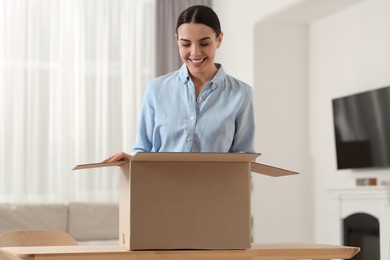 Happy young woman with opened parcel at home. Internet shopping