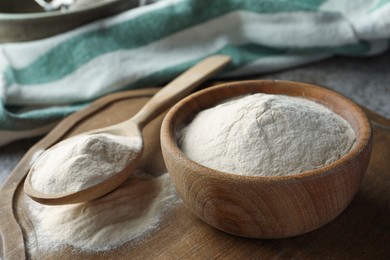 Photo of Bowl and spoon of agar-agar powder on grey table, closeup