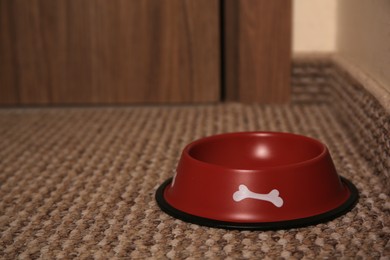 Empty red feeding bowl on soft carpet indoors. Space for text