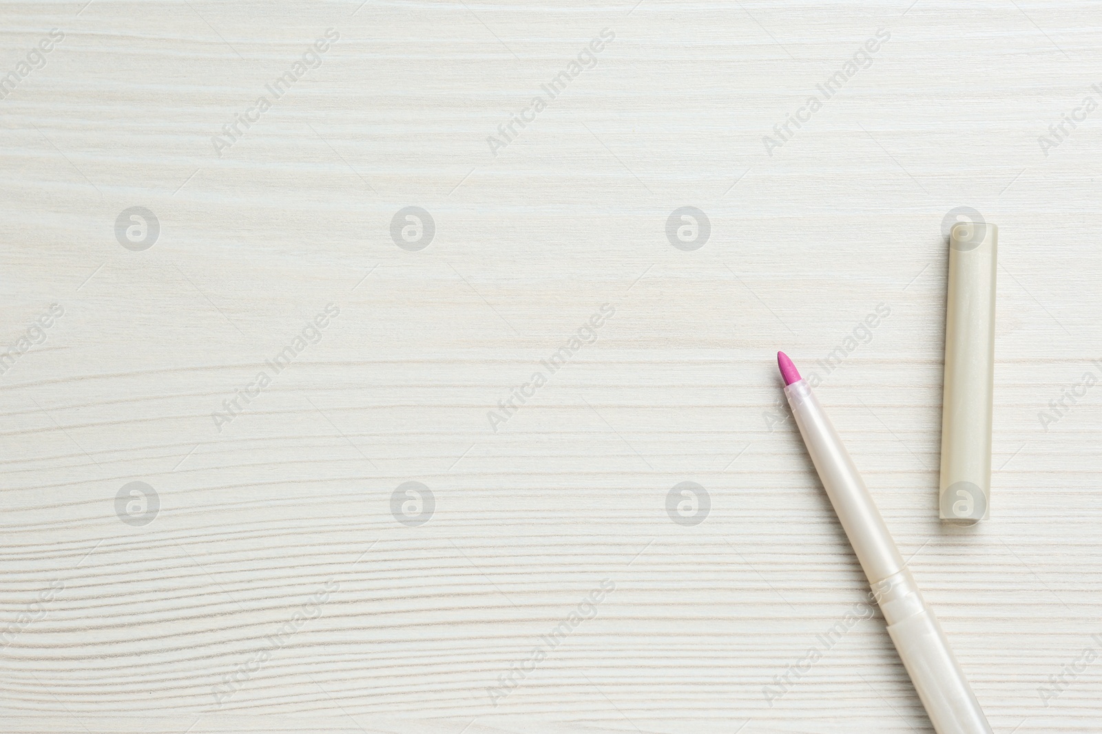 Photo of Bright lip pencil on white wooden table, flat lay. Space for text