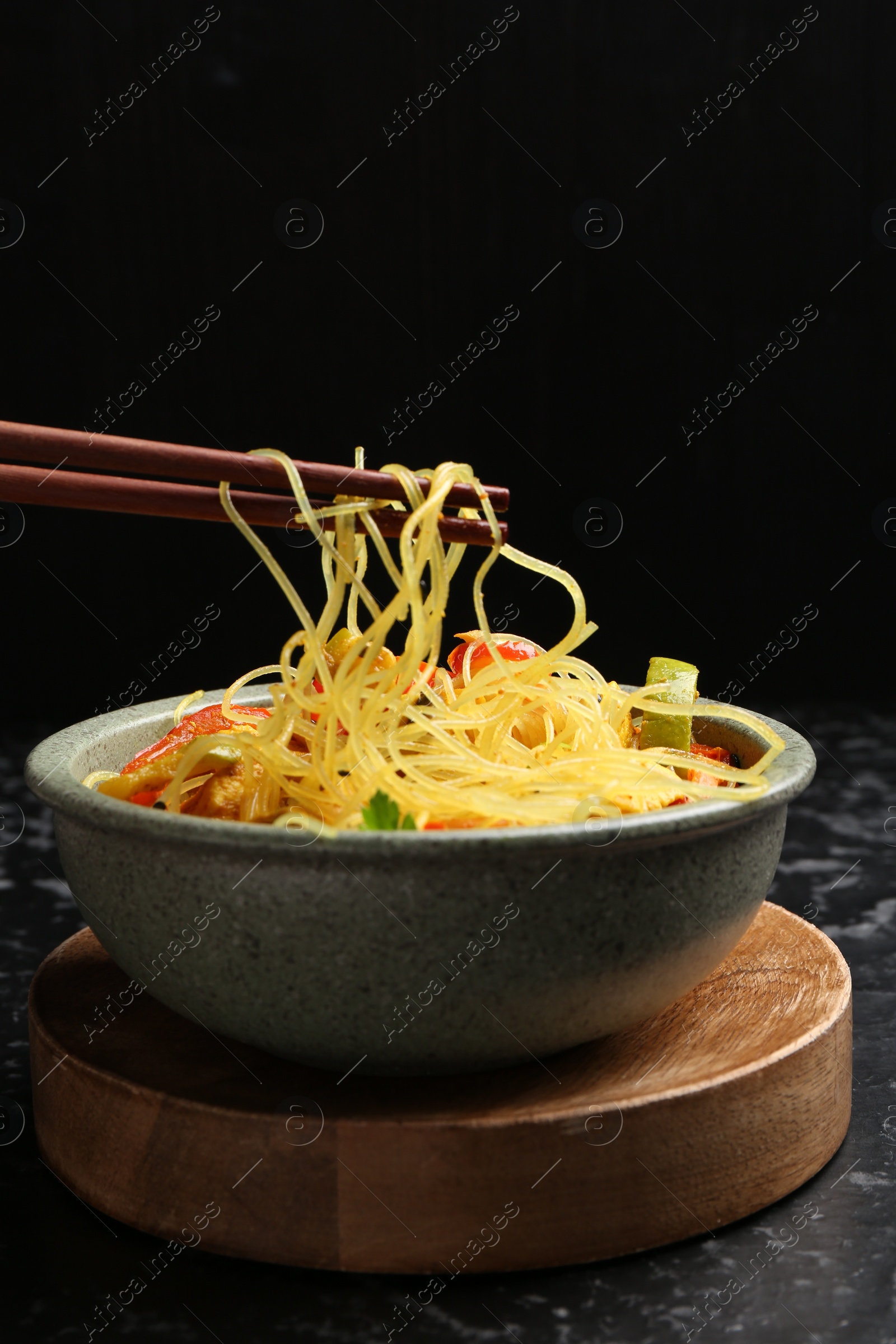 Photo of Stir-fry. Eating tasty noodles with meat and vegetables at dark textured table