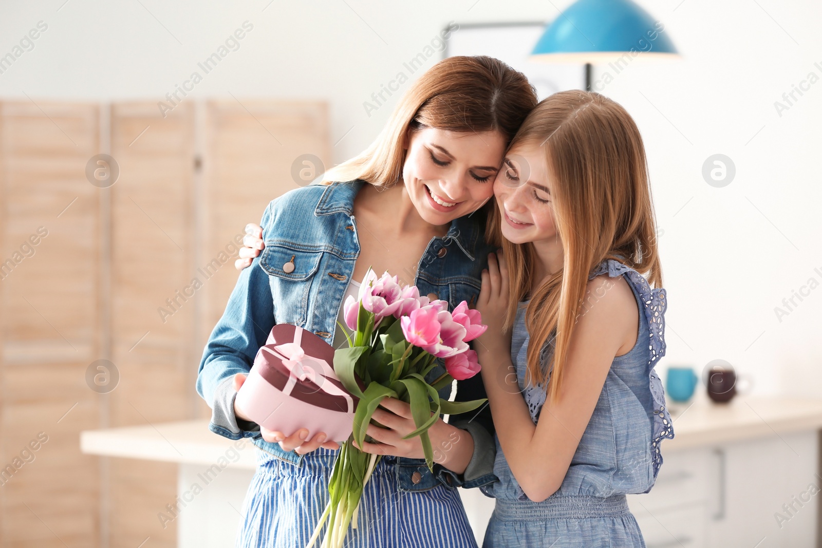 Photo of Teenage daughter congratulating happy woman on Mother's Day at home