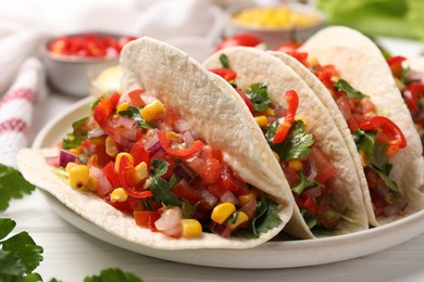 Photo of Tasty tacos with vegetables on white wooden table, closeup