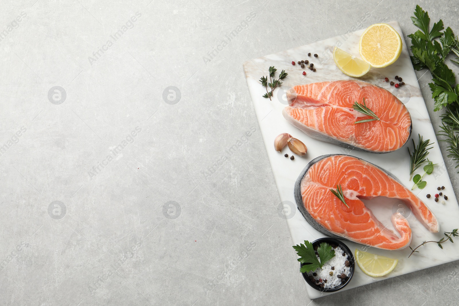 Photo of Fresh salmon and ingredients for marinade on light grey table, top view. Space for text