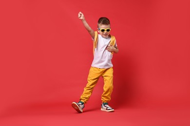 Happy little boy dancing on red background