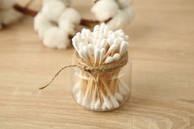 Cotton swabs and flowers on wooden table, closeup