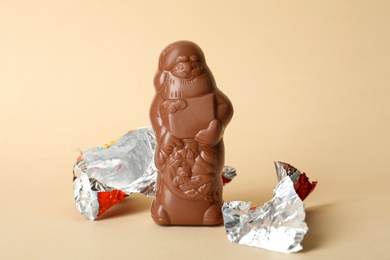 Unwrapped chocolate Santa Claus on beige background