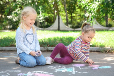 Photo of Little children drawing with colorful chalk on asphalt
