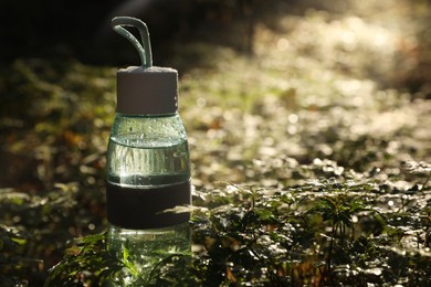 Photo of Glass bottle of water in green grass on sunny day. Space for text
