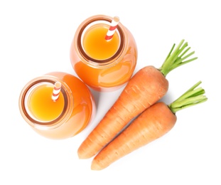 Photo of Freshly made carrot juice in glass bottles on white background, top view