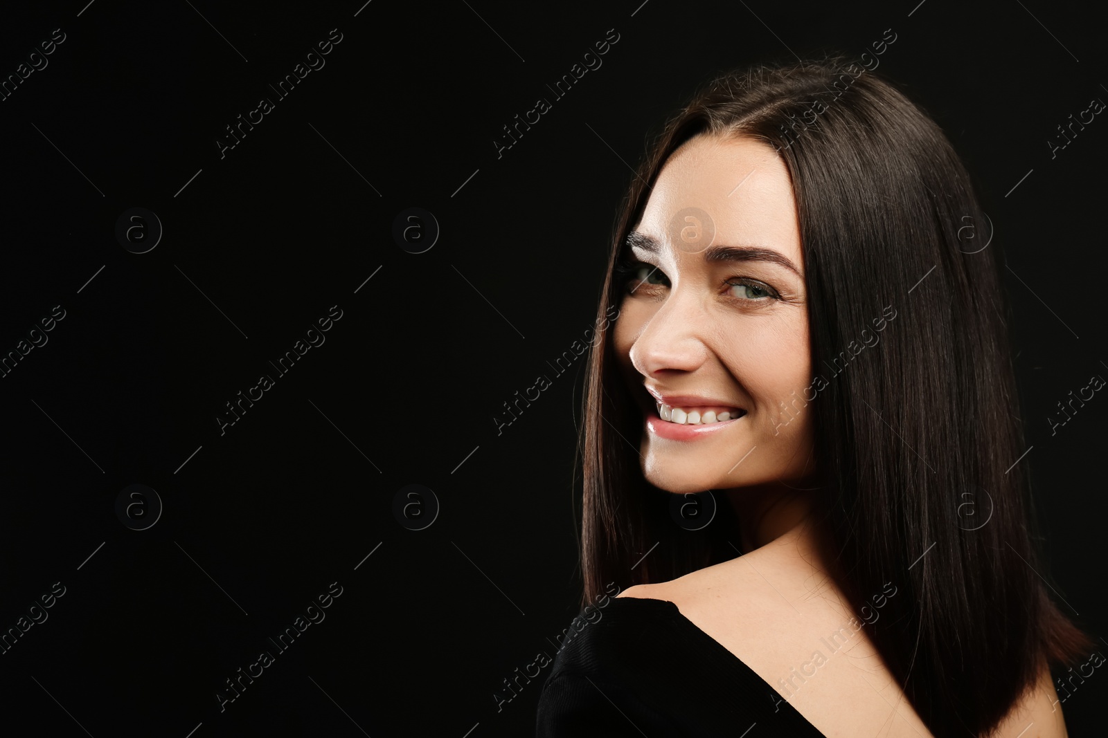 Photo of Portrait of pretty young woman with gorgeous chestnut hair and charming smile on black background, space for text