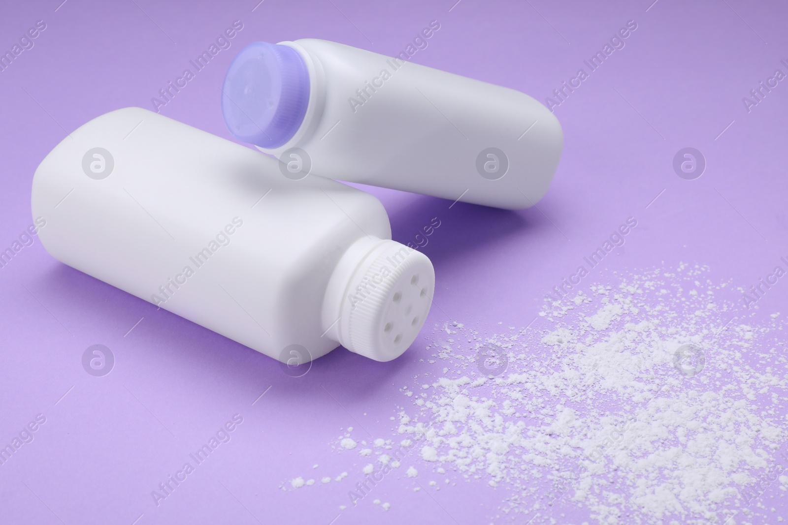 Photo of Bottles and scattered dusting powder on violet background. Baby cosmetic products