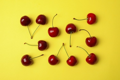 Photo of Many ripe sweet cherries on yellow background, flat lay