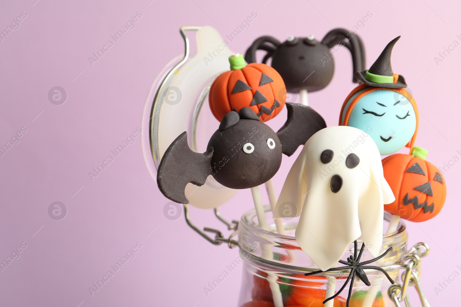 Photo of Delicious Halloween themed cake pops on pink background, closeup. Space for text