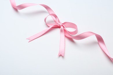 Photo of Pink satin ribbon with bow on white background, top view