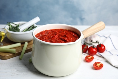 Photo of Delicious tomato sauce in pan on white wooden table