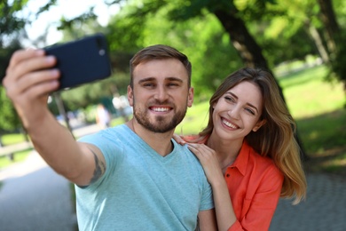 Photo of Happy young couple taking selfie in park