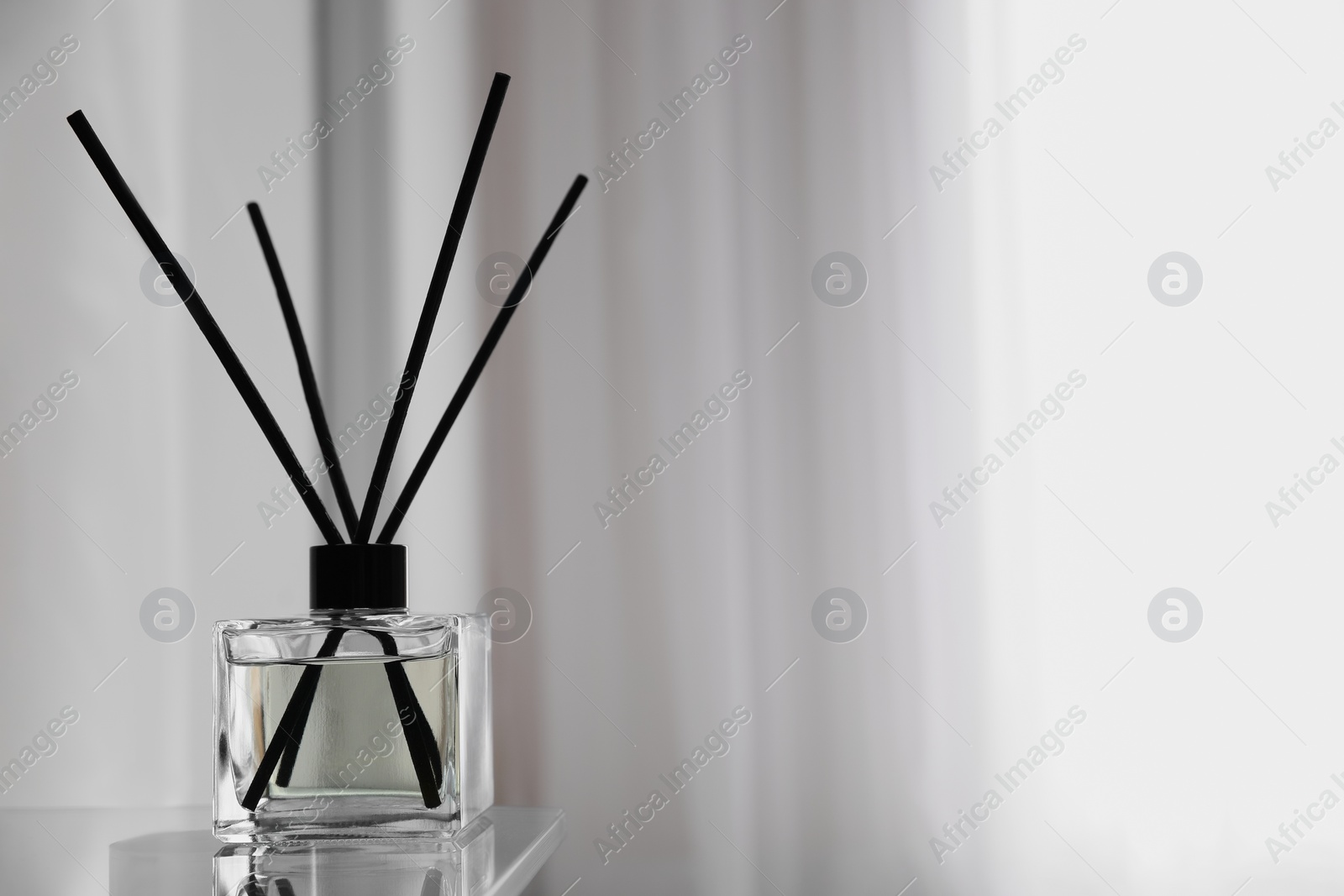 Photo of Aromatic reed air freshener on table indoors, space for text