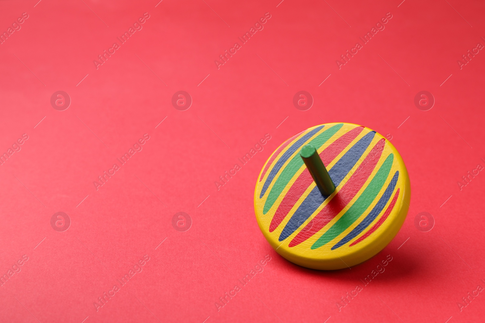 Photo of One colorful spinning top on red background, space for text