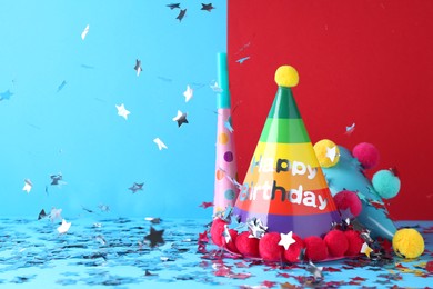 Photo of Party hats and confetti on color background, space for text