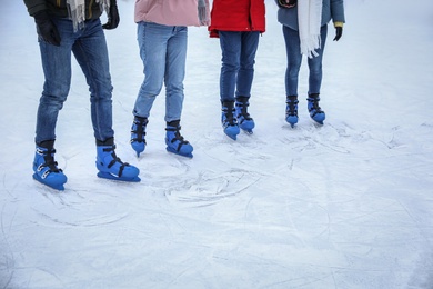 Photo of Friends skating along ice rink outdoors, closeup. Space for text