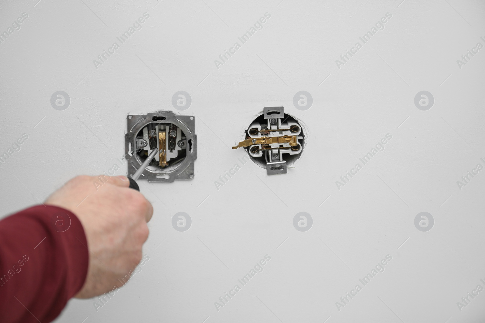 Photo of Electrician repairing wall sockets on white background, closeup