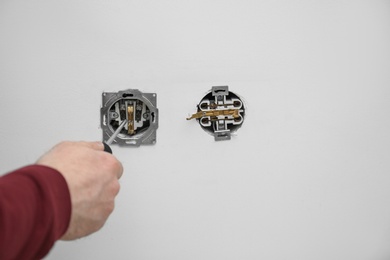 Electrician repairing wall sockets on white background, closeup