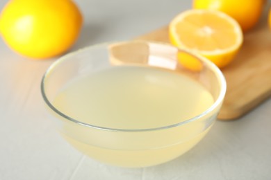 Photo of Freshly squeezed lemon juice in bowl on light table, closeup