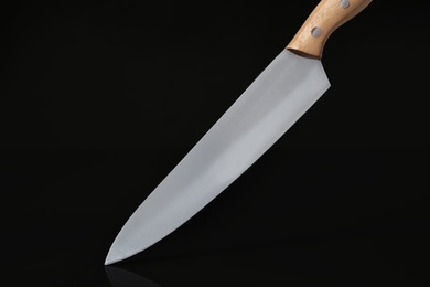 Photo of Sharp knife with wooden handle on black background