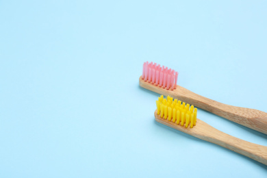 Photo of Toothbrushes made of bamboo on light blue background. Space for text