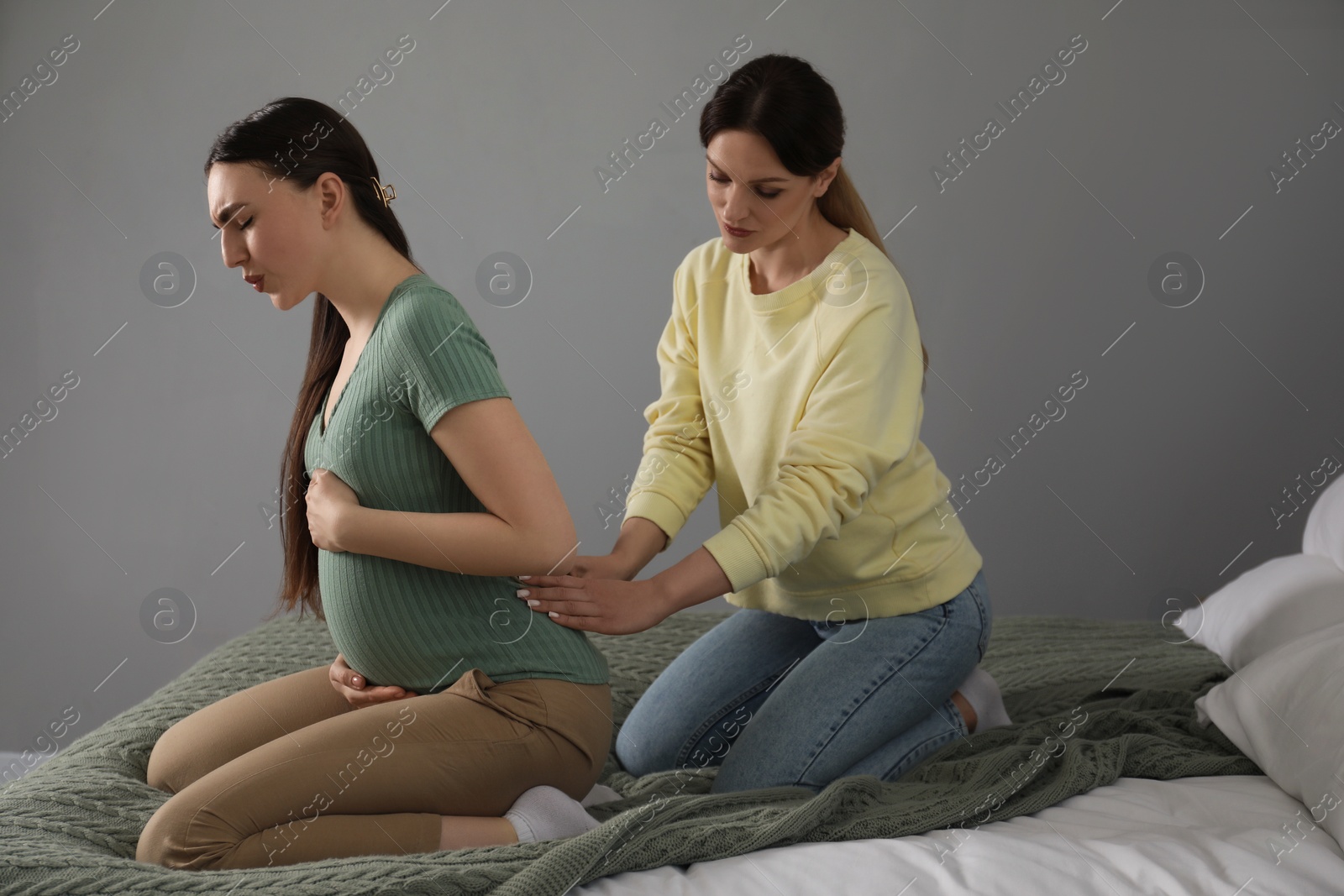 Photo of Doula massaging pregnant woman in bedroom. Preparation for child birth