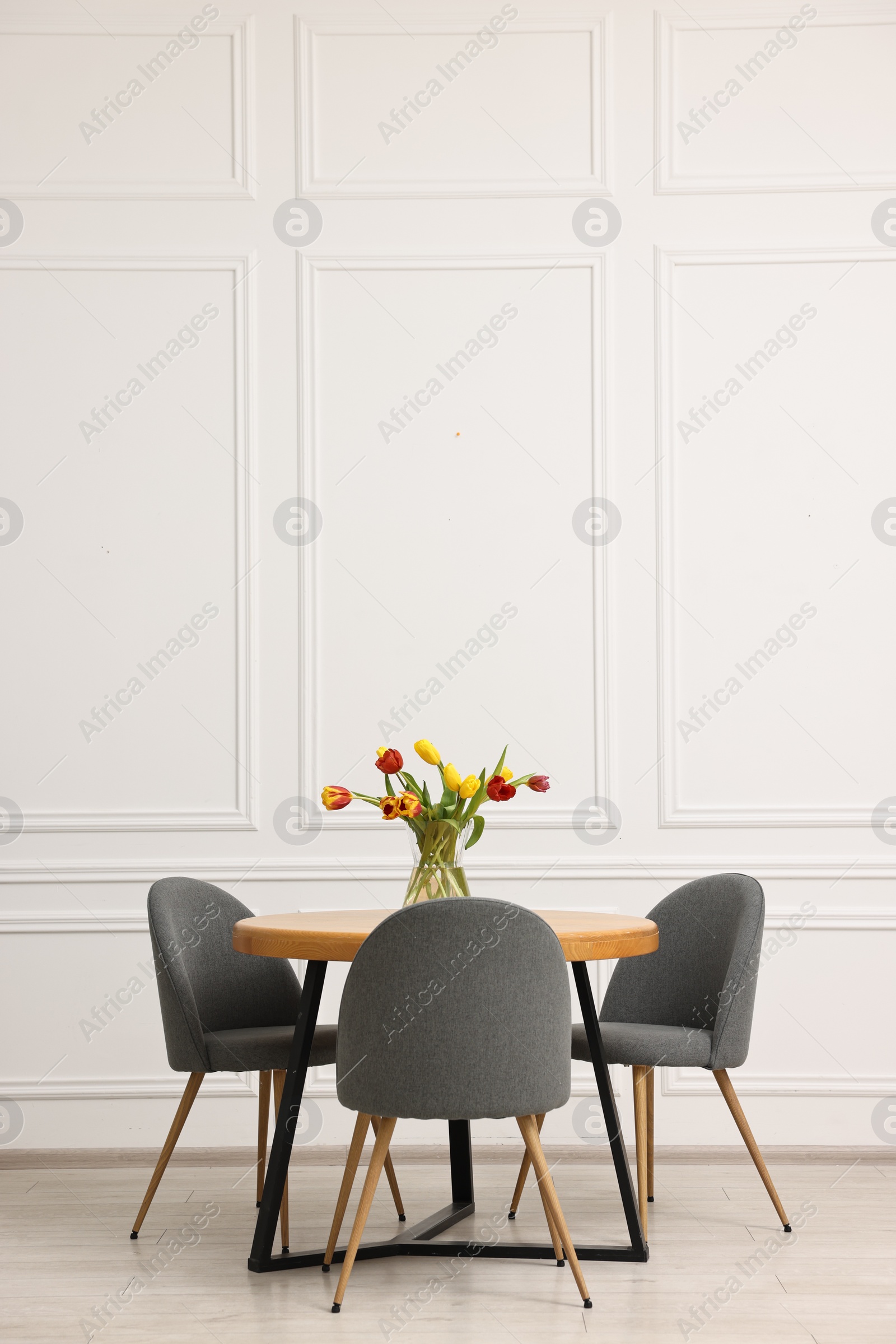 Photo of Stylish dining room interior with comfortable furniture and beautiful tulips. Space for text