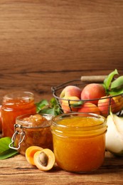 Photo of Jars with different jams and fresh fruits on wooden table