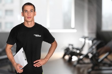 Image of Portrait of professional personal trainer with clipboard in gym. Space for text