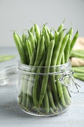 Photo of Fresh green beans in glass jar on grey wooden table, closeup
